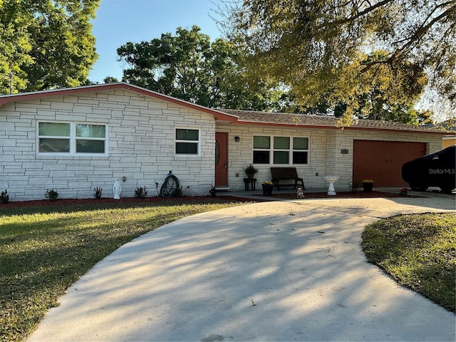 ranch-style house featuring an attached garage, concrete driveway, and a front yard