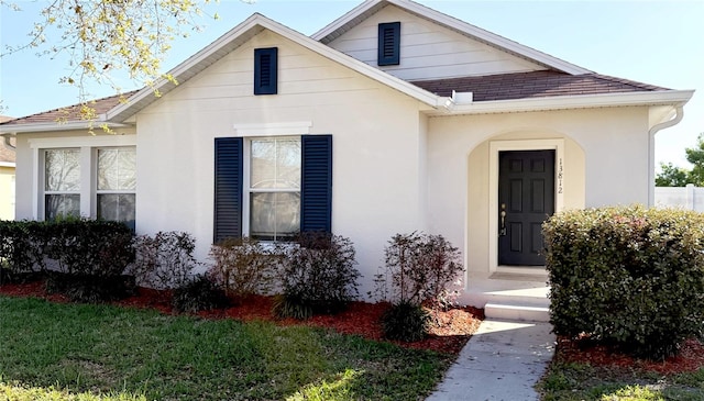 bungalow-style home featuring a front lawn and stucco siding