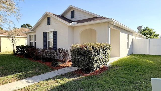 view of side of home with a lawn, fence, and stucco siding