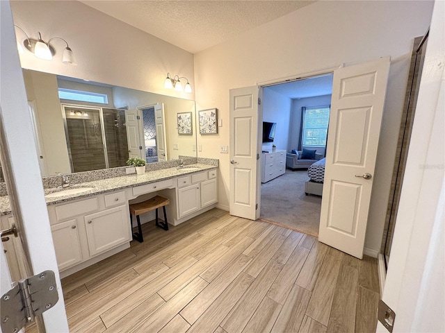 bathroom with hardwood / wood-style flooring, vanity, walk in shower, and a textured ceiling