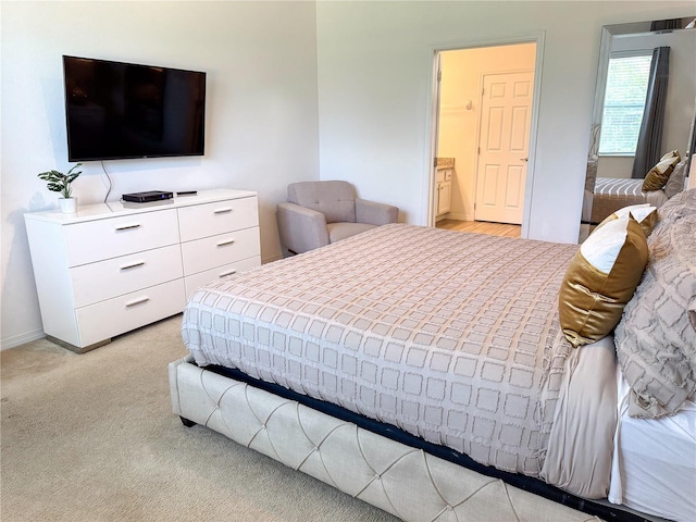 bedroom featuring light colored carpet and ensuite bathroom