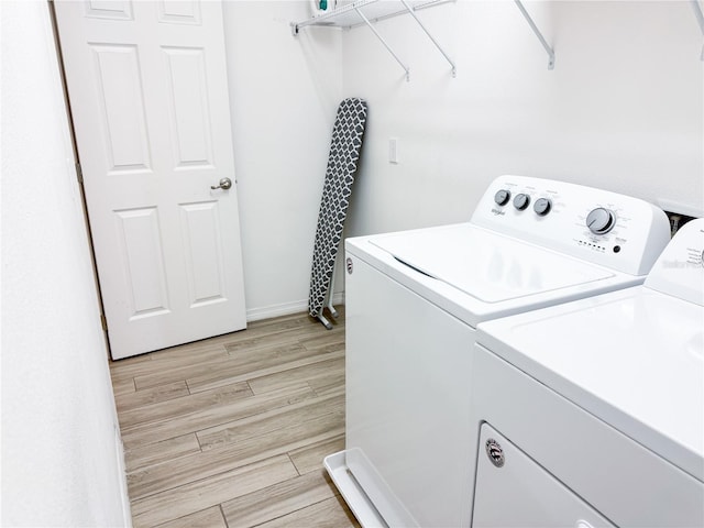 laundry room featuring independent washer and dryer and light hardwood / wood-style flooring