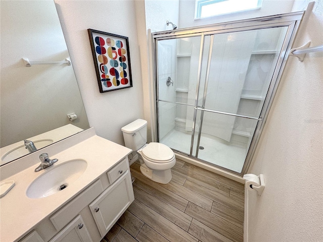 bathroom featuring vanity, a shower with shower door, and toilet