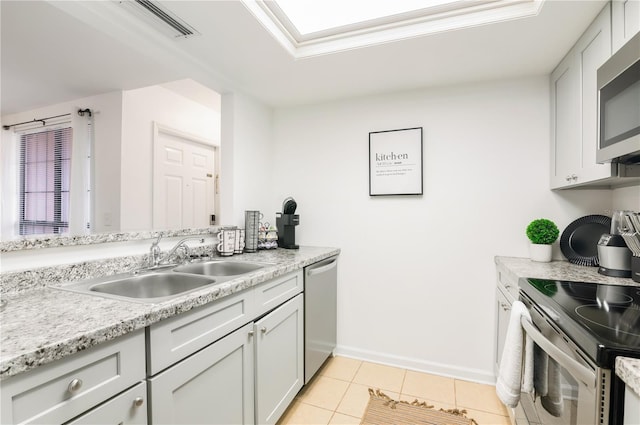 kitchen featuring appliances with stainless steel finishes, light stone countertops, sink, and light tile patterned floors