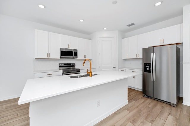 kitchen featuring sink, white cabinets, a kitchen island with sink, light hardwood / wood-style floors, and stainless steel appliances