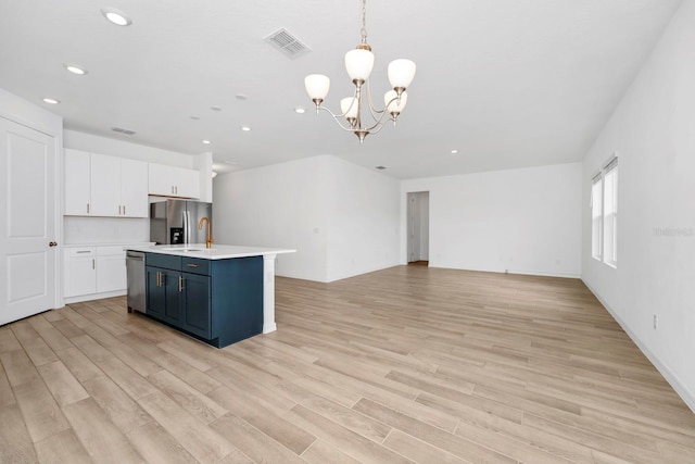 kitchen featuring white cabinetry, an inviting chandelier, appliances with stainless steel finishes, pendant lighting, and light hardwood / wood-style floors