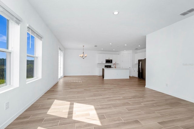 unfurnished living room featuring a notable chandelier