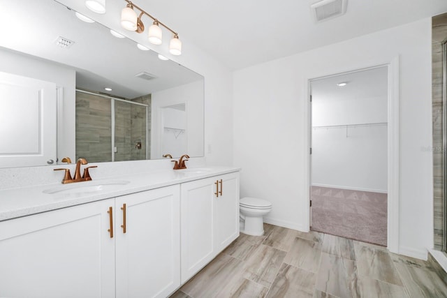 bathroom featuring a shower with door, vanity, and toilet