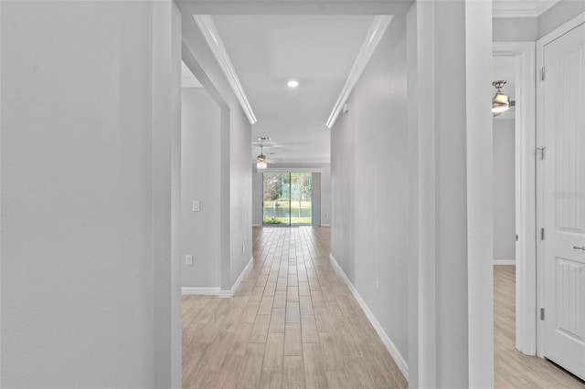 corridor with light wood finished floors, ornamental molding, and baseboards