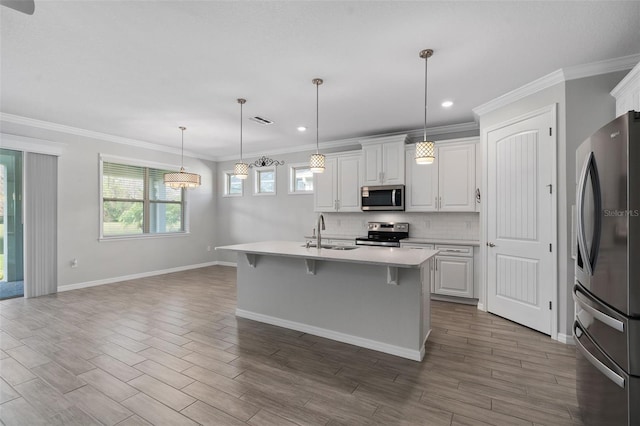 kitchen featuring appliances with stainless steel finishes, white cabinetry, sink, hanging light fixtures, and a kitchen island with sink