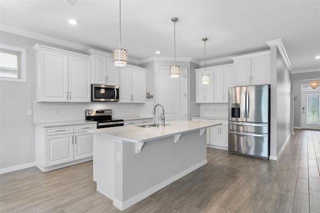 kitchen featuring a breakfast bar, white cabinetry, sink, hanging light fixtures, and stainless steel appliances