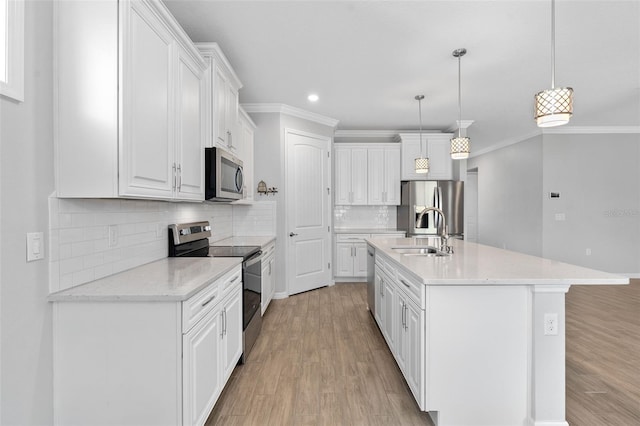 kitchen with pendant lighting, sink, appliances with stainless steel finishes, an island with sink, and white cabinets