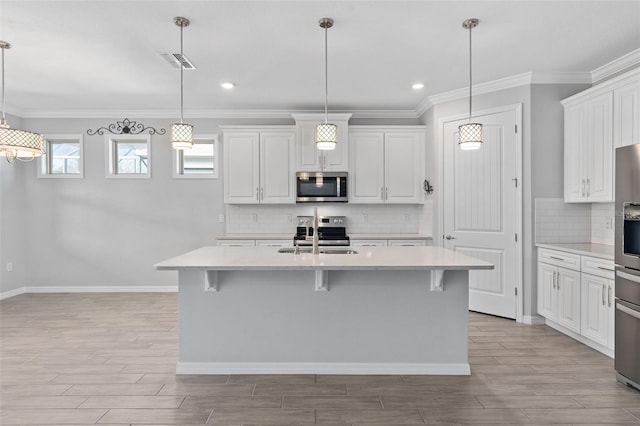 kitchen with a sink, visible vents, a kitchen breakfast bar, light countertops, and appliances with stainless steel finishes