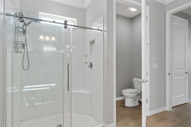 bathroom with ornamental molding, wood-type flooring, a shower with shower door, and toilet