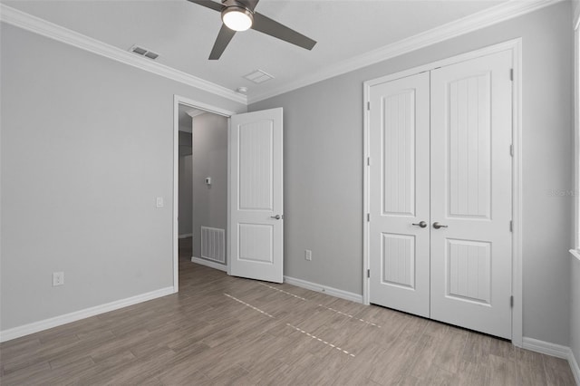 unfurnished bedroom featuring ornamental molding, ceiling fan, light hardwood / wood-style floors, and a closet