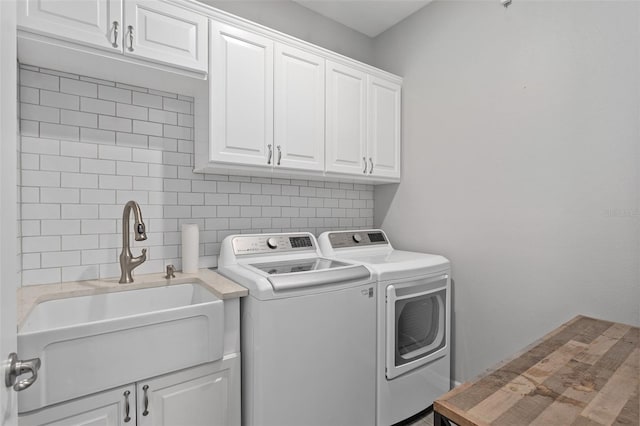 clothes washing area featuring cabinets, sink, and washer and clothes dryer