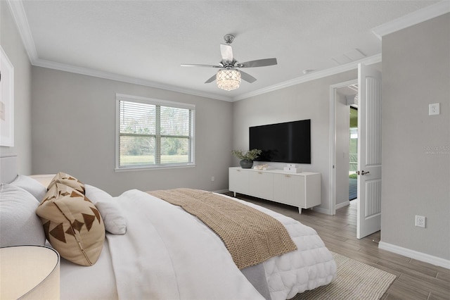 bedroom featuring baseboards, ceiling fan, wood finished floors, crown molding, and a textured ceiling