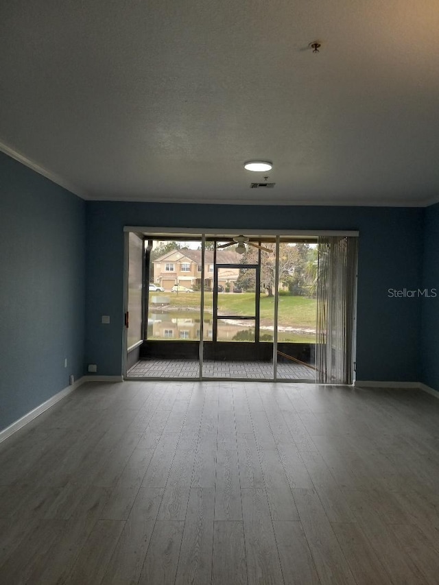 empty room with ornamental molding and wood-type flooring