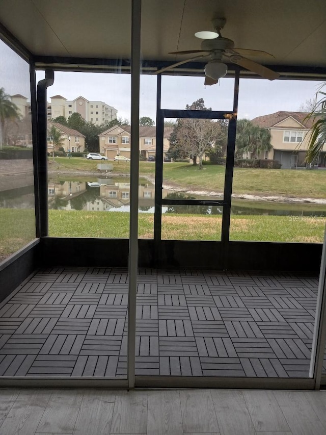 unfurnished sunroom featuring a water view, ceiling fan, and plenty of natural light