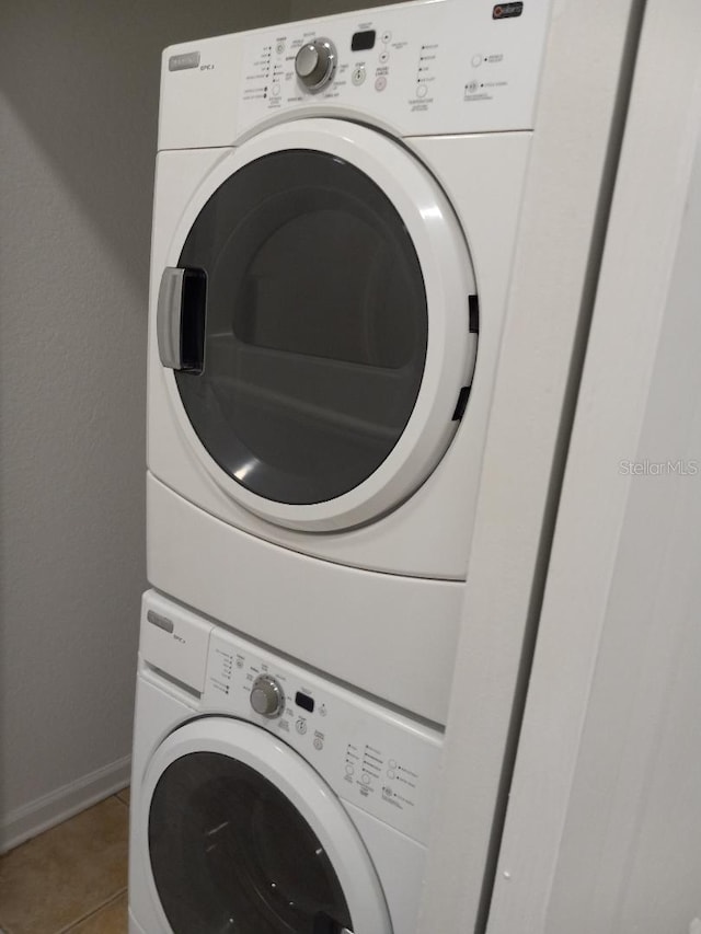 clothes washing area featuring stacked washer / drying machine and tile patterned floors