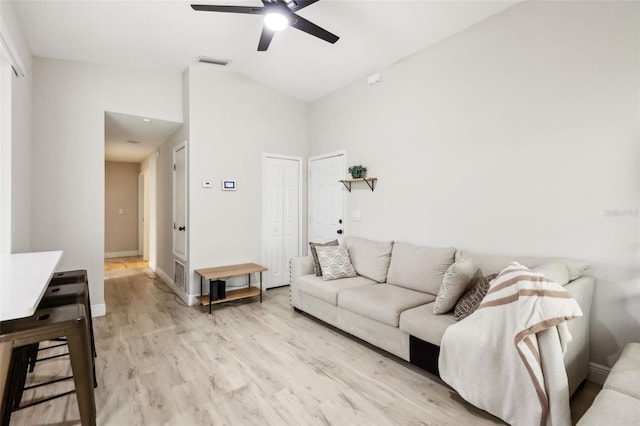 living room with ceiling fan, lofted ceiling, and light hardwood / wood-style floors