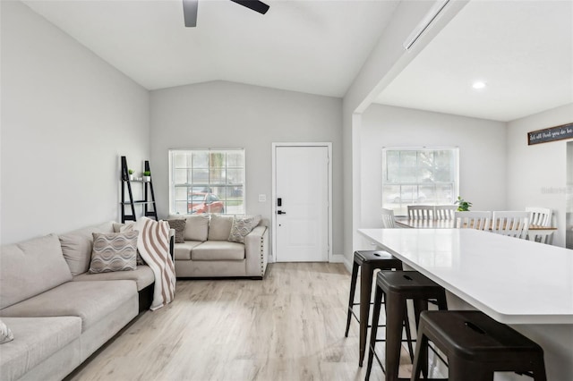 living room featuring ceiling fan, lofted ceiling, and light hardwood / wood-style flooring