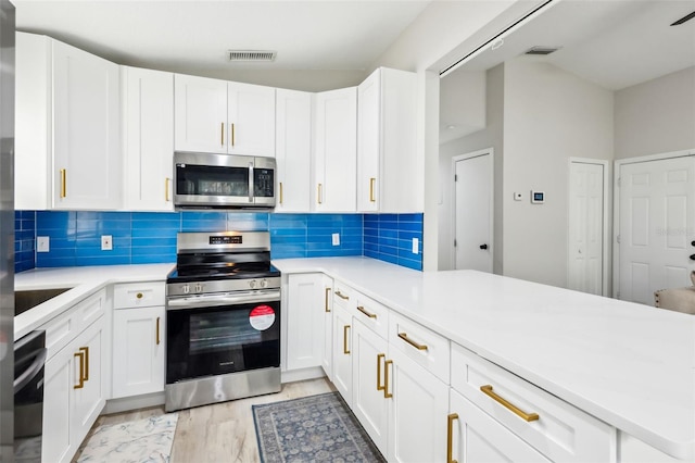 kitchen featuring kitchen peninsula, white cabinets, and appliances with stainless steel finishes