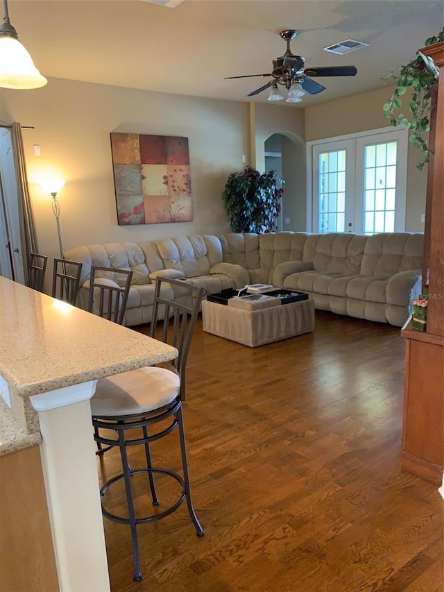 living area featuring arched walkways, wood finished floors, visible vents, and ceiling fan