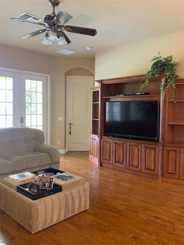 living area featuring light wood-style flooring, a ceiling fan, and visible vents