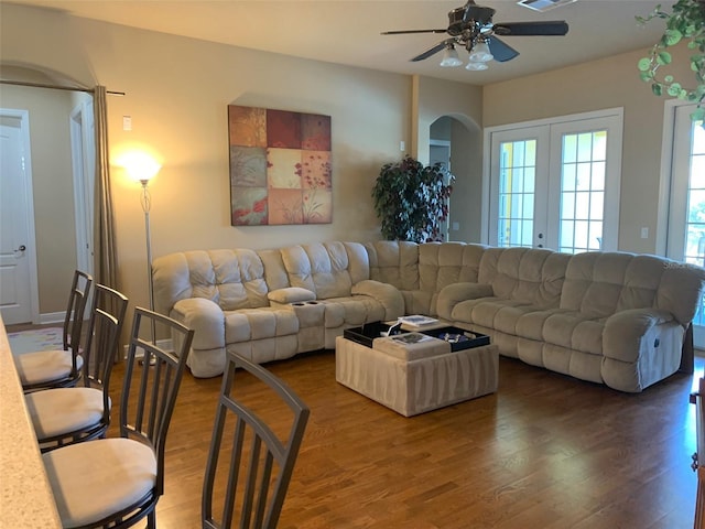 living room featuring a ceiling fan, visible vents, wood finished floors, arched walkways, and french doors