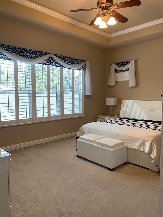 bedroom with ceiling fan, baseboards, carpet, a tray ceiling, and ornamental molding