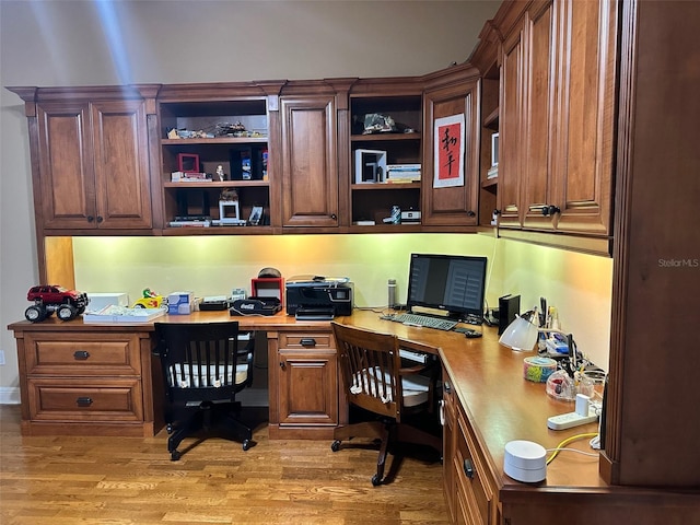 home office with built in study area and light wood-style floors