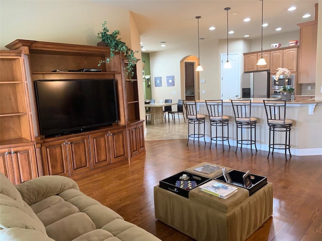 living area featuring recessed lighting, arched walkways, and wood finished floors
