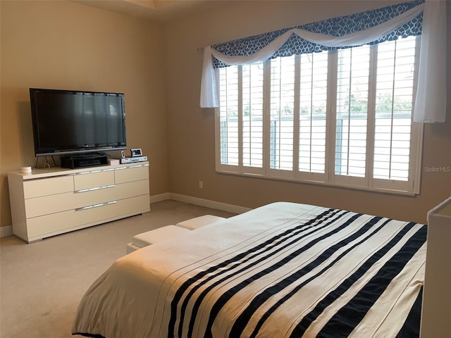 bedroom with baseboards and light carpet