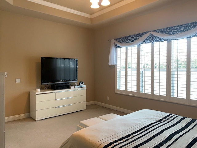 bedroom with crown molding, baseboards, a raised ceiling, and light carpet