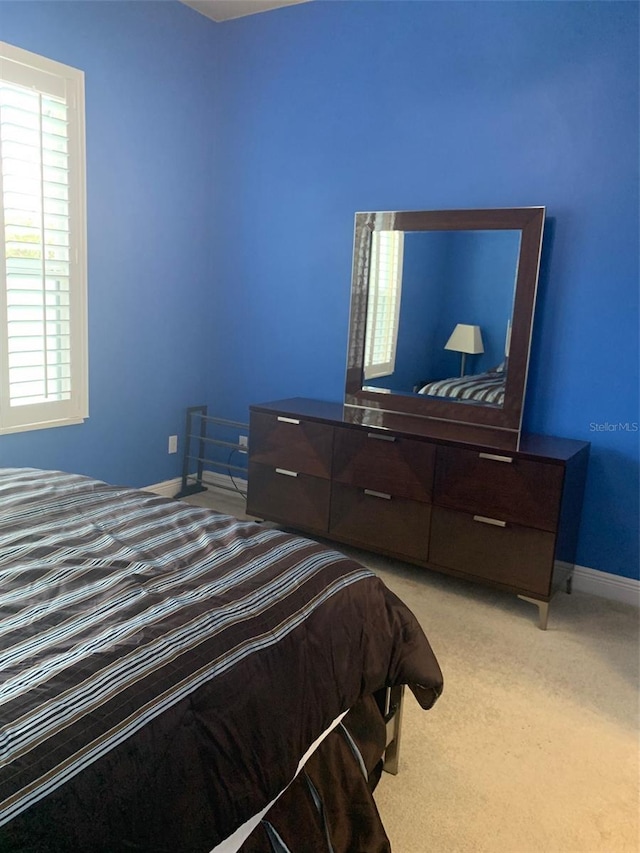 bedroom with light colored carpet and baseboards