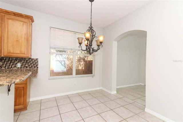 unfurnished dining area featuring light tile patterned floors and a notable chandelier