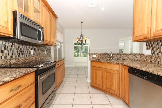 kitchen featuring stainless steel appliances, sink, light tile patterned floors, and dark stone counters