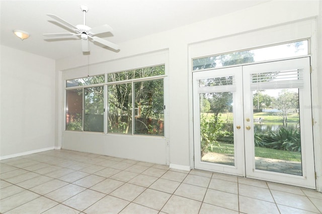 unfurnished sunroom with a water view, ceiling fan, and french doors