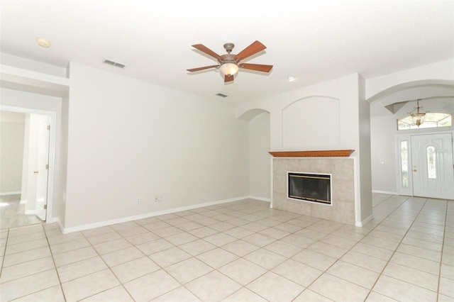 unfurnished living room with ceiling fan, a tiled fireplace, and light tile patterned floors