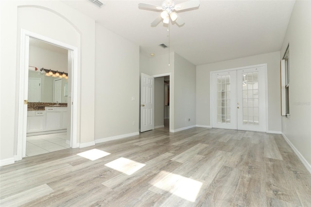 empty room with vaulted ceiling, light hardwood / wood-style flooring, ceiling fan, and french doors