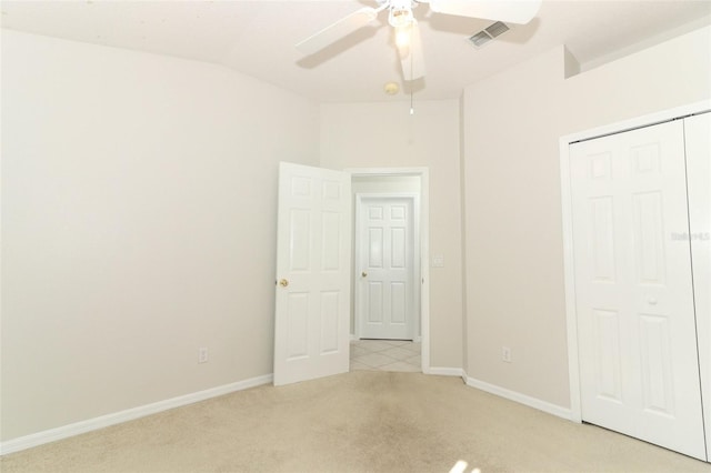 unfurnished bedroom featuring lofted ceiling, light colored carpet, ceiling fan, and a closet