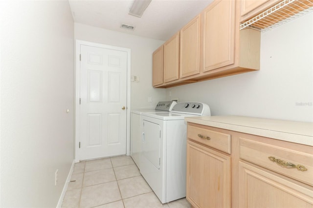 clothes washing area with cabinets, independent washer and dryer, and light tile patterned floors