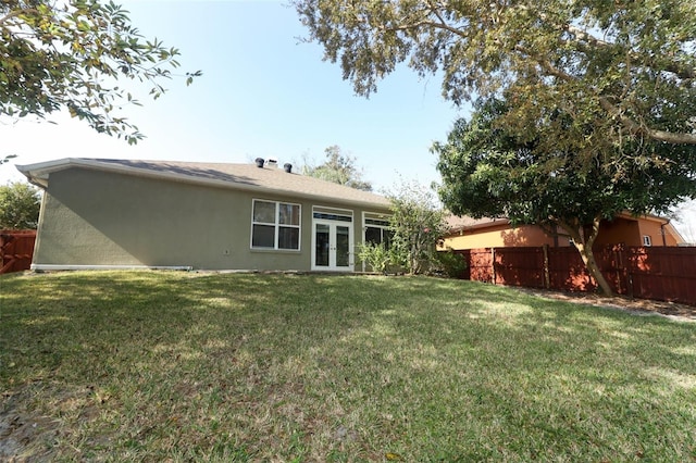 back of house featuring a yard and french doors