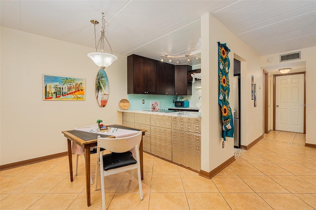 kitchen with pendant lighting, light tile patterned floors, stainless steel fridge, dark brown cabinetry, and kitchen peninsula