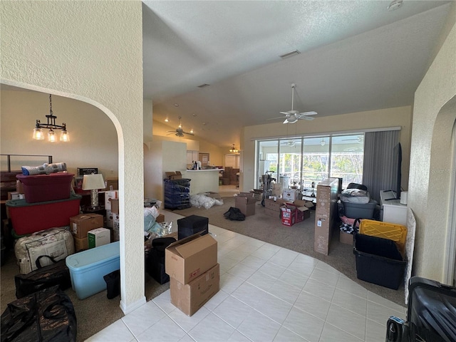 living room with ceiling fan with notable chandelier, light colored carpet, and vaulted ceiling