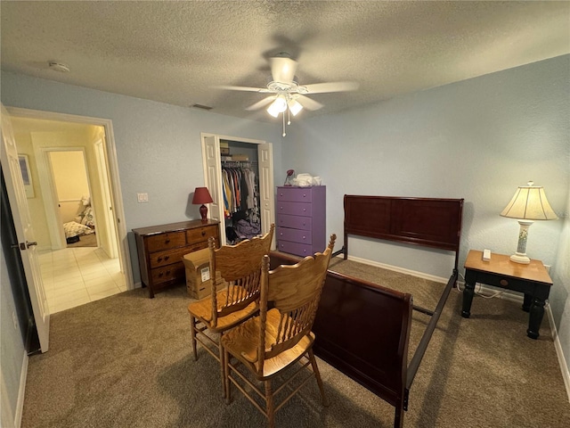 carpeted bedroom with ceiling fan, a closet, a textured ceiling, and a walk in closet