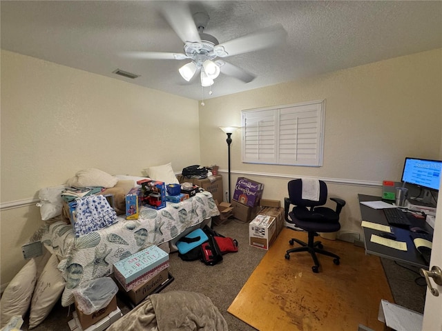 carpeted home office with ceiling fan and a textured ceiling