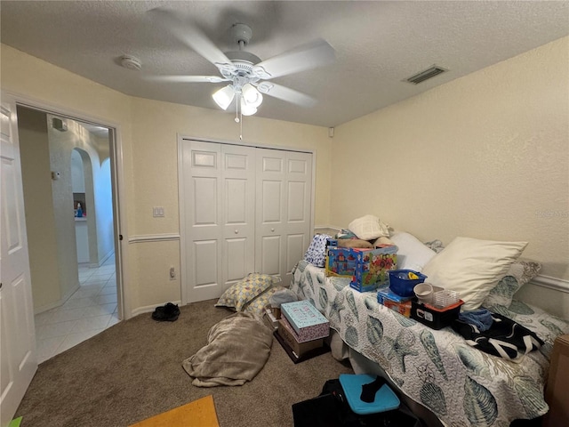 carpeted bedroom featuring ceiling fan, a textured ceiling, and a closet