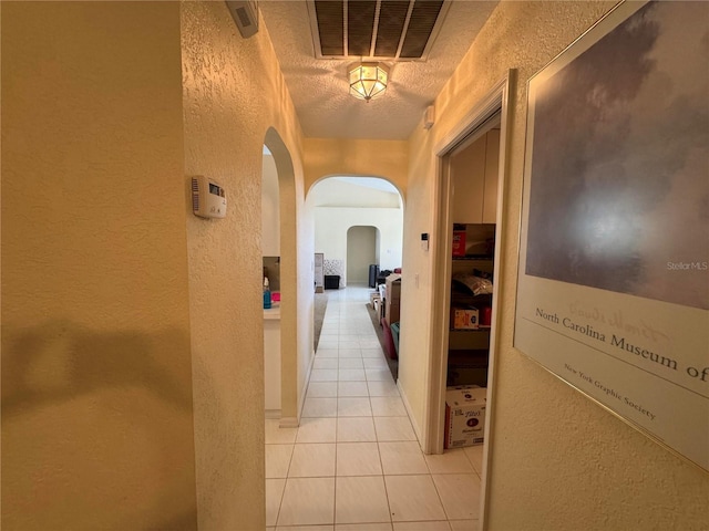 corridor with light tile patterned floors and a textured ceiling